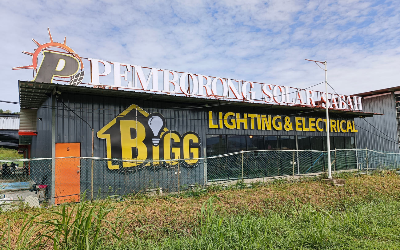 The Kolombong warehouse, its roofline carrying the fabricated letters Pemborong Solar Sabah and the BIGG Lighting & Electrical mark.
